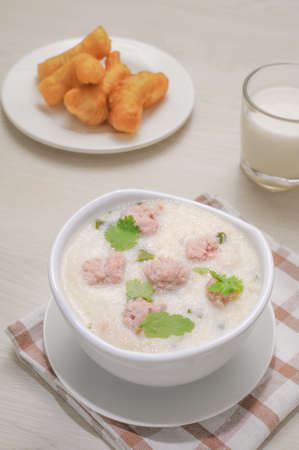 Thai Breakfast, Boiled rice with pork in white bowl on wooden table.の写真素材