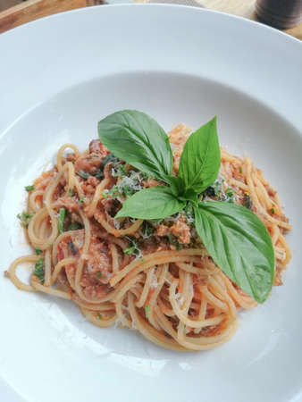 Spaghetti tomato sauce with pork and Basil in a white plate.の写真素材