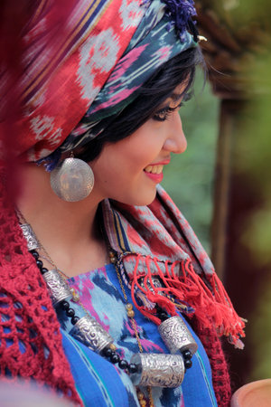Close-up of a beautiful Asian model dressed in modern batik with a distinctive Lombok pattern, smiling looking to the side with red lips and curled eyelashes.のeditorial素材