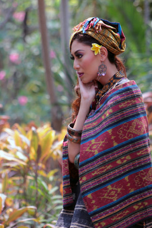 Portrait of beautiful Asian Woman in traditional Indonesian clothing complete with assorted accessories posing against a green park in the background.のeditorial素材