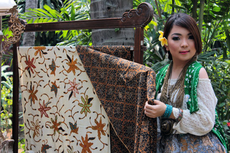 Portrait of typical Indonesian Batik held by a young Asian woman wearing traditional Indonesian clothing complete with accessories.のeditorial素材