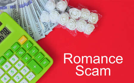Top view calculator, fake money, miniature white roses with text ROMANCE SCAM. Financial and crime concept.の写真素材