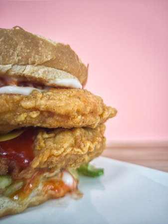 Double fried chicken burger with eggs, mayo, salad, cheese and chilli sauce. Selective focus points. Blurred backgroundの写真素材
