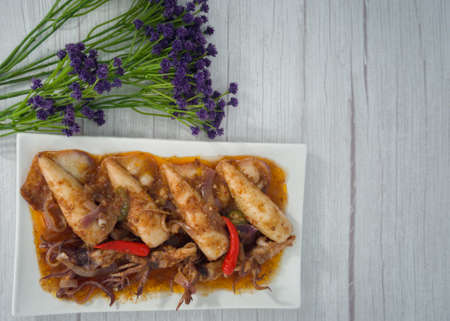 A serving of squid sambal on a white plate. Selective focus points. Blurred background