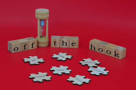Layout of scattered puzzles, hourglass and wooden cubes with text OFF THE HOOK. Financial and business concept. Selective focus pointsの写真素材