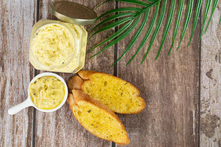 A few slice of garlic bread with a small bowl and an opened jar of garlic butter spread. Selective...