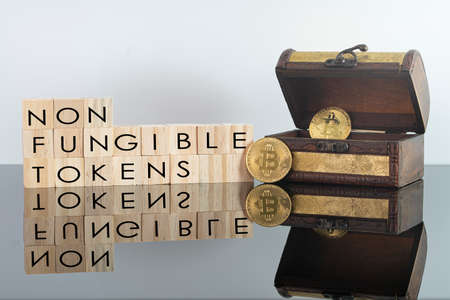 Digital currency concept. Non fungible tokens text on wooden blocks with bitcoins and chestの写真素材