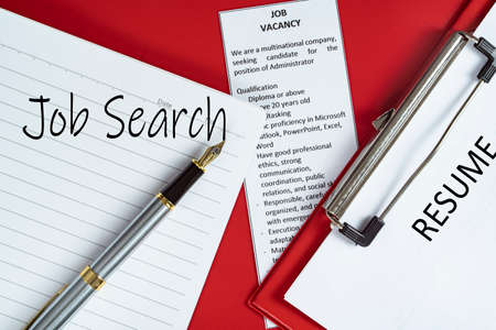 Business concept - layout of notebook, advertisement, pen and resume on clipboard with text Job searchの写真素材
