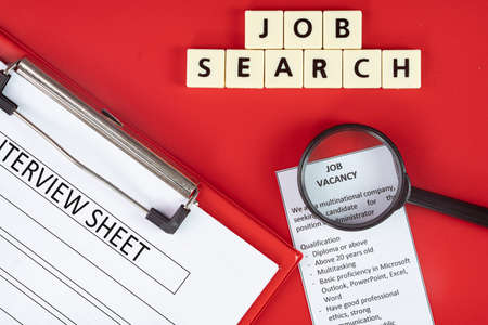Business concept - layout of magnifying glass, advertisement, Interview sheet on clipboard and tiles with text Job searchの写真素材