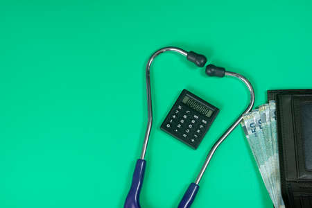 Medical and business concept. Layout of stethoscope, calculator and wallet with cash reference to medical bills. Selective focus pointsの写真素材