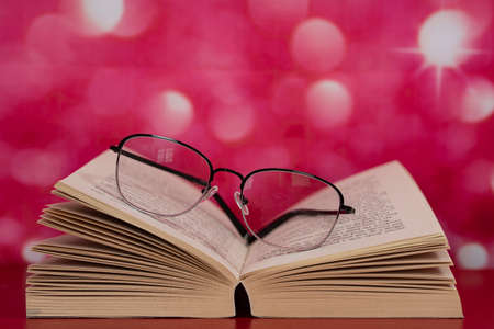 An open book with glasses on top of the pages. Selective focus points. Blurred backgroundの写真素材