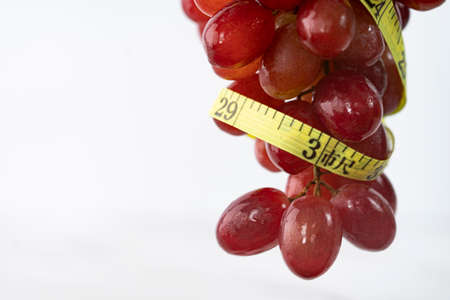Close-up of a bunch of freshly washed grapes with measuring tape. Selective focus points.