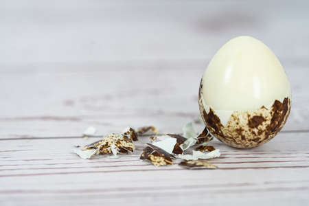 Close-up of a peeled hard boiled quail egg with broken shell. Selective focus points.の写真素材