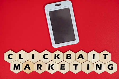 Mobile phone replica with wooden hexagon tiles and text Clickbait Marketing. Clickbait is a method...
