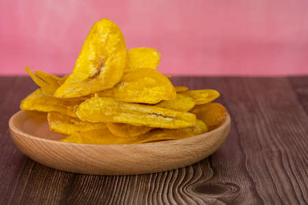 Banana chip or locally known as kerepek pisang in a wooden plate. Selective focus points. Blurred backgroundの写真素材
