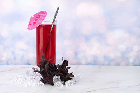 A glass of Roselle drinks with metal straw and whole roselle fruitsの写真素材