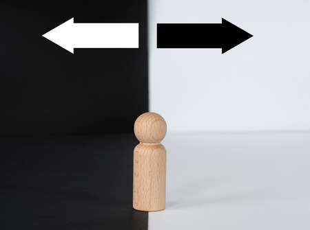 Business concept. Decision making portrayed by a wooden figure with two arrows on black and white background. Selective focus points.の写真素材