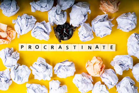 Business concept. Layout of pocket watch, crumpled papers and tiles with text procrastinateの写真素材