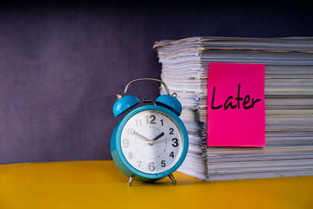 Business concept. Layout of alarm clock, stack of papers and note with text Later reference to procrastinateの写真素材