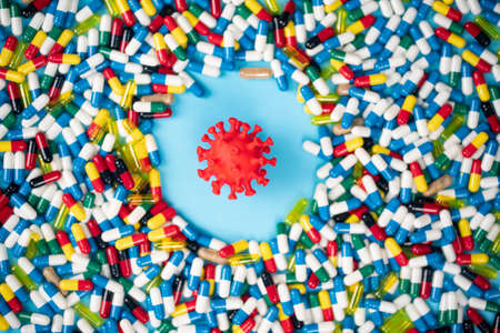 Studies to introduce anti-covid pills to fight the virus. Model of virus surrounded by various pills. Health concept. Selective focus pointsの写真素材