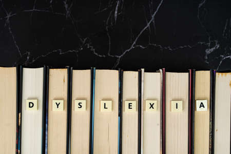 Plastic tiles with letters spelling DYSLEXIA on book. Dyslexia is a reading disorder. Learning conceptの写真素材