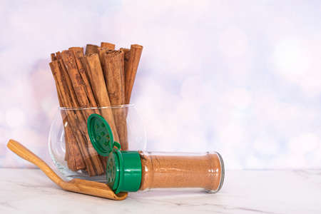 Some cinnamon sticks in a glass bowl and a bottle of cinnamon powder with wooden spatula. Selective...
