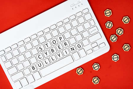 Layout of a keyboard with text STOP CYBER BULLYING and wooden tiles with stop emoji. Cyberbullying conceptの写真素材