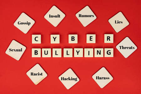 Layout of plastic tiles with text CYBER BULLYING and wooden tiles with texts of cyberbullying actions. Cyberbullying conceptの写真素材