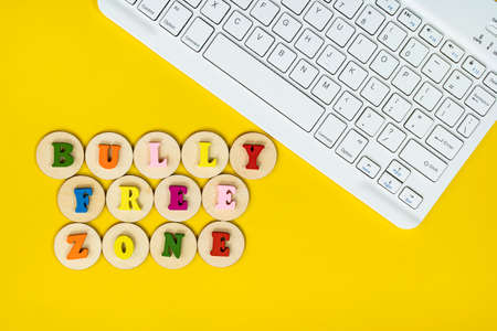 Layout of wooden alphabet on wooden tiles, keyboard with text BULLY FREE ZONE. Cyberbullying conceptの写真素材