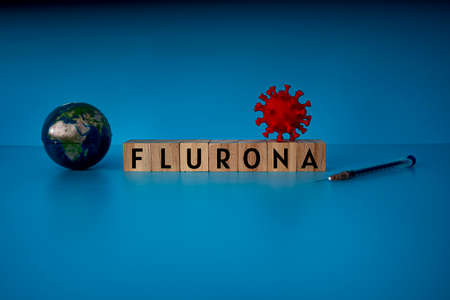 Health concept. Layout of small globe, virus model, syringe and wooden blocks with text FLURONA, new dual infection detected.の写真素材