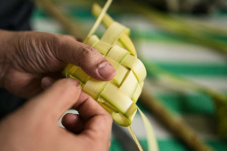 Weaving the coconut leaves making the ketupat, a traditional Malay cuisine during the Eid celebration. Selective focus pointsの写真素材