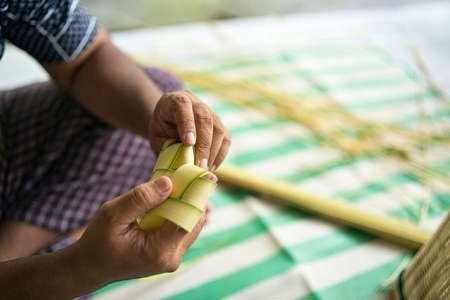 Weaving the coconut leaves making the ketupat, a traditional Malay cuisine during the Eid celebration. Selective focus pointsの写真素材