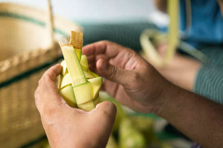 Weaving the coconut leaves making the ketupat, a traditional Malay cuisine during the Eid celebration. Selective focus pointsの写真素材