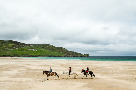 Horseback riding on a white sand beach in Irelandのeditorial素材