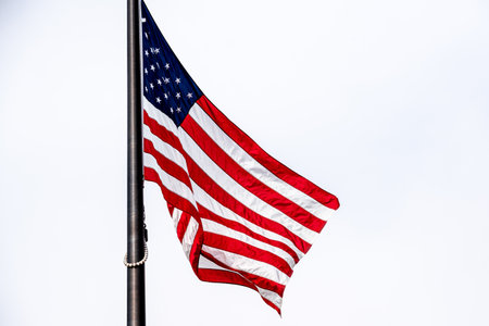American flag waving in the wind on a pole against a blue sky