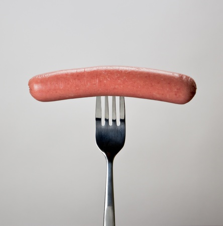 Sausage on the fork over gray background.の写真素材