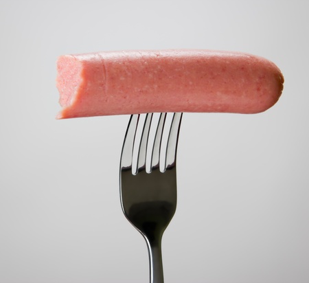 Sausage on the fork over gray background.の写真素材