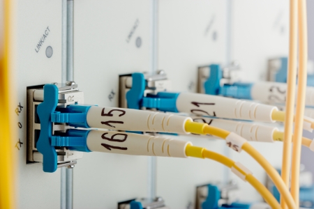 Modern internet router in data center with 10G interface cards, XFP modules and single mode fiber optic patch cord in ports. Focus on port.の写真素材