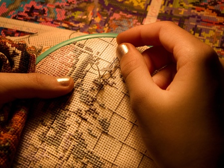 Low key. Warm light. Embroidery close-up. Children's hands.の写真素材