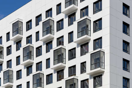 A multi-storey condominium in a laconic white design. Balconies on the facade of a new residential...
