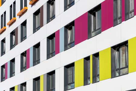 The multi-colored facade of a high-rise residential building. Rows of windows