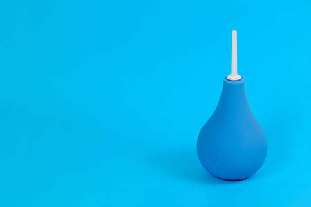 Blue pear-shaped enema with white tip on light blue background, copy space. Colon cleansing concept. Background for medical announcementの写真素材