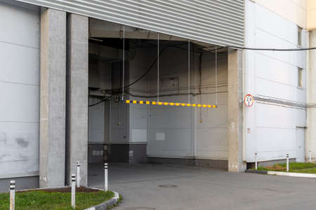 Height limiter of passing vehicles. Entry for vehicles with limited height. Grey building of the enterprise. Yellow long height restriction stripe. Entry of high vehicles is prohibitedの写真素材