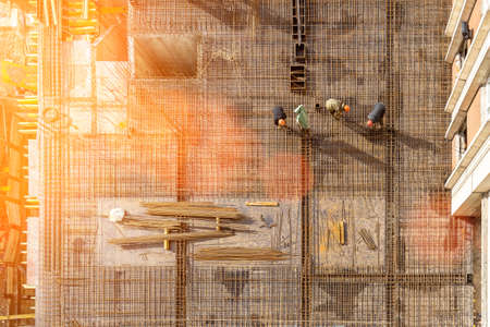Concrete work at the construction site. Construction workers wearing helmets lay steel reinforcement...