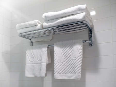Clean white towels on a shelf in the bathroom in a hotel room. Close-up bath accessoriesの写真素材