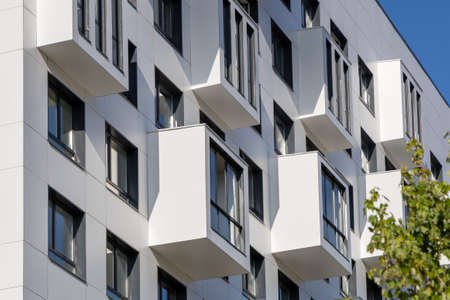 Compact balconies on the white facade of the condominium. Multi-storey apartments. Small living...