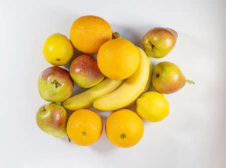 Top view of fresh fruit on a white background. Bananas, orange, lemon and pears on a white surface. The concept of proper and healthy nutritionの写真素材