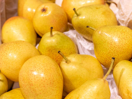 Yellow pears are in a box of white paper. Selling fruit at a grocery store, market, or grocery...