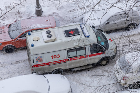 Russian ambulance in snowy gloomy weather. White ambulance minibus in winter. Moscow, Russia - January 26, 2022のeditorial素材