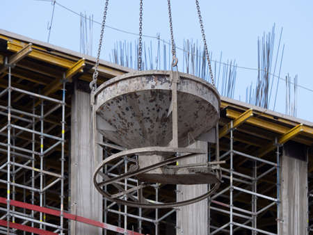 Tank with concrete mortar. Crane lifting concrete container on construction site. Cast-in-place concrete. Construction of monolithic buildings and structuresの写真素材
